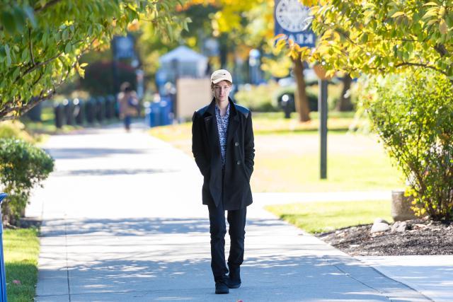 A young man walks along Cougar Walk in the Fall
